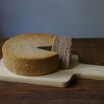 Para fazer um Bolo de Leite Quente com massa branca simples, combine farinha, açúcar, ovos, manteiga e leite quente. O leite